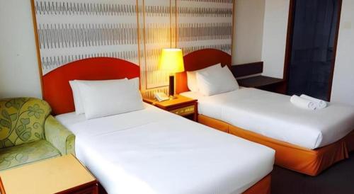a hotel room with two beds and a lamp at Pelican Hotel in Batu Pahat