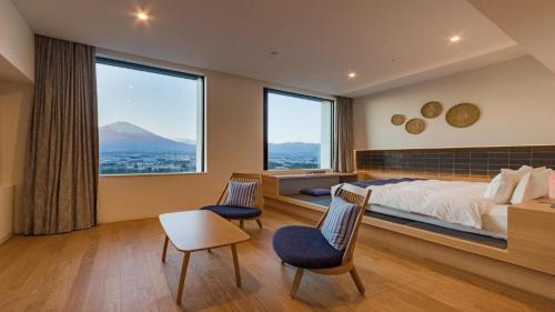 a bedroom with a bed and two chairs and a large window at HOTEL CLAD in Fuji