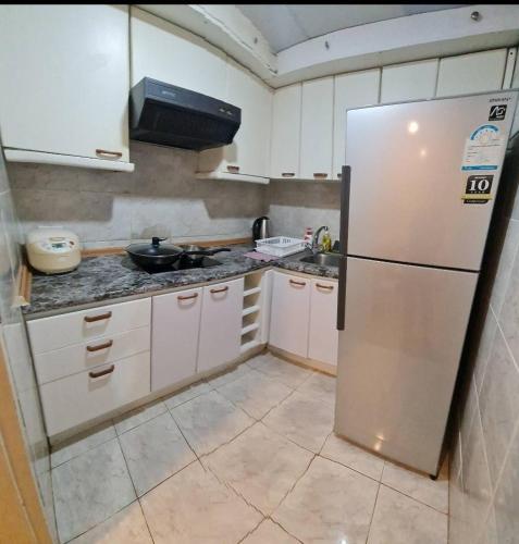 a kitchen with white cabinets and a refrigerator at Comfort 1BR 2 King Beds, Best Value Stay, near Bts Nana in Bangkok