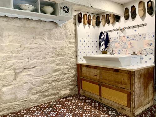 a kitchen with a sink and a stone wall at La Grange avec Jacuzzi in Loguivy-Plougras