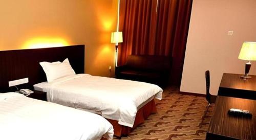 a hotel room with two beds and a chair at Eminent Hotel in Kota Kinabalu