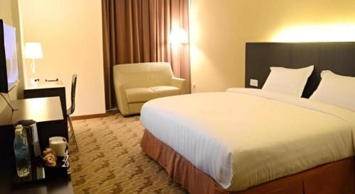 a hotel room with a large bed and a chair at Eminent Hotel in Kota Kinabalu