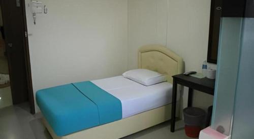 a small bedroom with a bed and a table at Rafayeh Hotel in Seremban