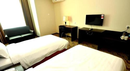 a hotel room with two beds and a flat screen tv at Eminent Hotel in Kota Kinabalu