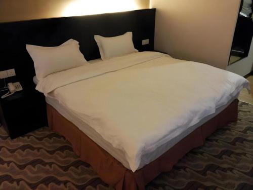 a large bed with white sheets and pillows in a room at Eminent Hotel in Kota Kinabalu