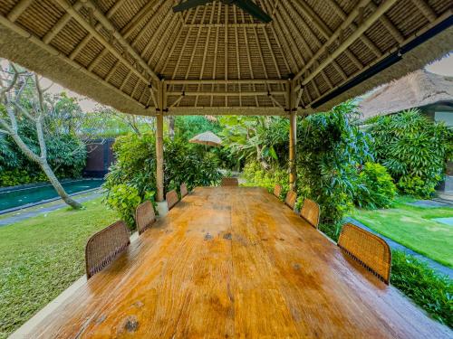 a wooden table with chairs and a large umbrella at Villa Blubambu in Seminyak