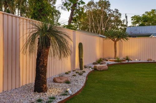 a palm tree in a yard next to a fence at The Little Tropicana in Byron Bay
