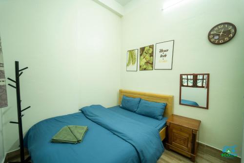 a bedroom with a blue bed and a clock on the wall at Cao Bang Eco Homestay in Cao Bằng