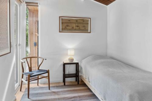 ein Schlafzimmer mit einem Bett, einem Stuhl und einem Tisch in der Unterkunft Cozy Holiday Home Near Rødby in Rødby