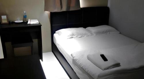 a bedroom with a bed with a cell phone on it at OYO 89780 Lodge 37 in Ranau