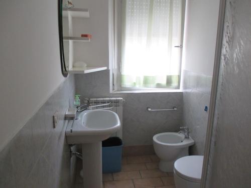 a bathroom with a sink and a toilet and a window at Parri Apartment in Follonica