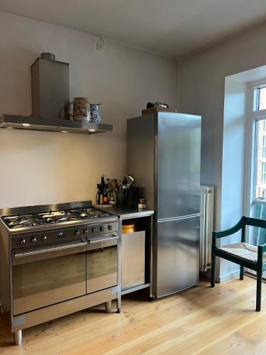 a kitchen with a stainless steel stove and refrigerator at Bright, child-friendly, balcony, 50 meters from the subway in Copenhagen