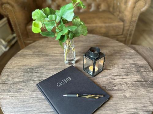 a table with a notebook and a pen and a vase at Grangärde Hotell in Grangärde