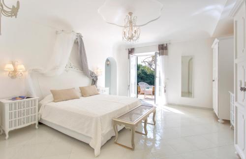 a white bedroom with a large bed and a chandelier at Villa dei Lecci - 7 Luxury villas with private pool or jacuzzi in Ischia