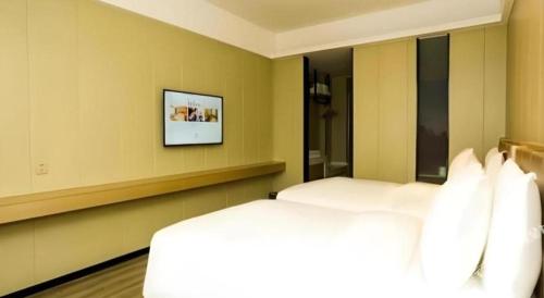 a bedroom with a bed and a television on the wall at Borrman Hotel Xiamen Xiang'an Maxiang in Xiamen