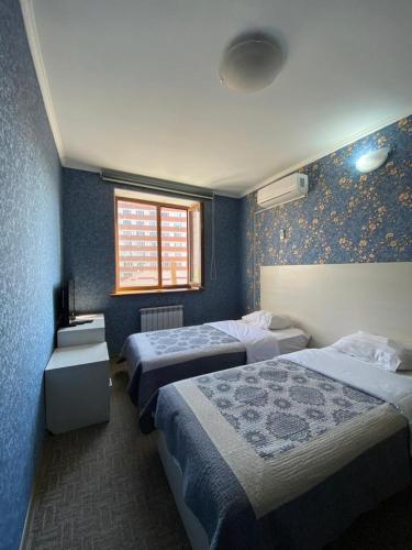Una habitación de hotel con dos camas y una ventana. en Shirin Botanik Hotel, en Bishkek
