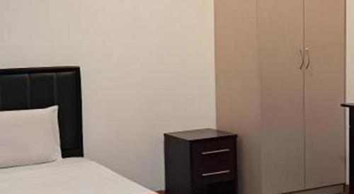 a bedroom with a bed with a nightstand and a white wall at OYO 90785 Pandan Hotel in Kota Kinabalu