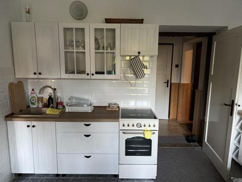a kitchen with white cabinets and a stove top oven at Chata Myslivna v centru Vysočiny Herálec in Žďár nad Sázavou