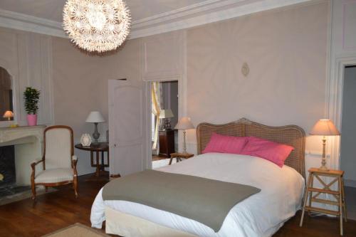 Un dormitorio con una cama grande y una lámpara de araña. en Ferme de la Vallière en Tancrou