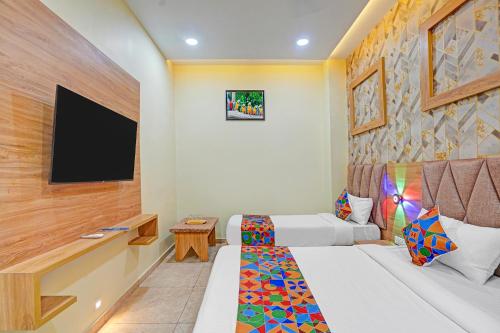 a hotel room with a bed and a flat screen tv at FabHotel Hill Top Inn in Ahmedabad