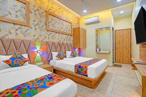 a hotel room with two beds and a television at FabHotel Hill Top Inn in Ahmedabad