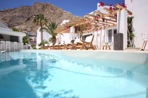 een zwembad met stoelen en een huis met een berg op de achtergrond bij Cavo Bianco Boutique Hotel & Spa in Kamari