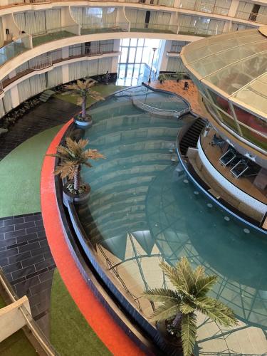an indoor swimming pool in a building with palm trees at belliza apartment in Surat
