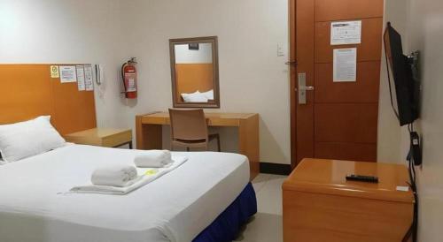 a bedroom with a bed and a desk and a television at Jeamco Royal Hotel - Pasig in Manila