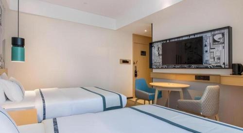 a hotel room with two beds and a flat screen tv at City Comfort Inn Ji'an South Administrative Center in Ji'an