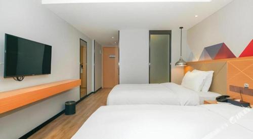 a hotel room with two beds and a flat screen tv at Borrman Hotel Zhuhai Gongbei Port Fuhuali Light Rail in Zhuhai