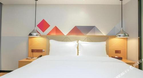a bedroom with a large white bed with two pillows at Borrman Hotel Zhuhai Gongbei Port Fuhuali Light Rail in Zhuhai