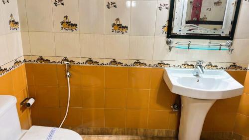 a bathroom with a sink and a mirror and a toilet at Hotel Ellora In Cooch Behar in Koch Bihār
