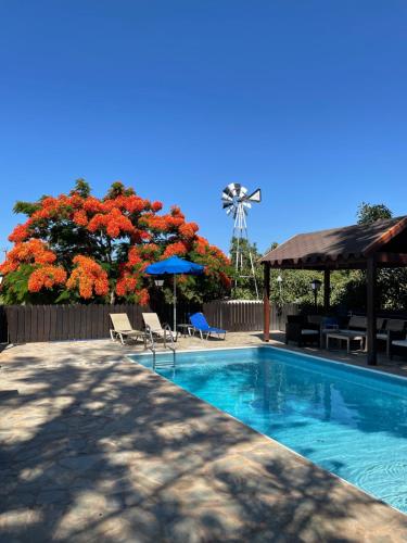 a swimming pool with chairs and a windmill in the background at Villa Filip Coral Bay in Peyia