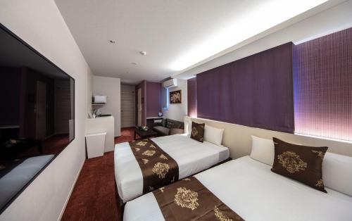 two beds in a hotel room with purple curtains at GRAND BASE Okayama Ekimae in Okayama