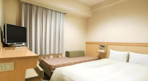 a hotel room with a bed and a desk with a television at Premier Hotel Cabin Matsumoto in Matsumoto