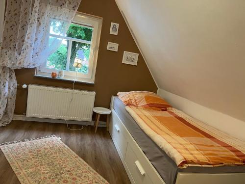 a small bedroom with a bed and a window at Ferienhaus "De lütten Tieden" 65358 in Moormerland