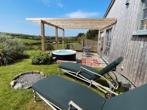 a patio with a hot tub and a table and chairs at The Dairy - Luxurious Hideaway on The Lizard in Cury
