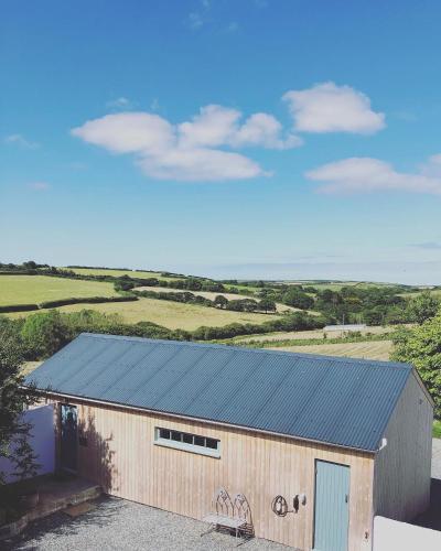 a large wooden building with a blue roof at The Dairy - Luxurious Hideaway on The Lizard in Cury