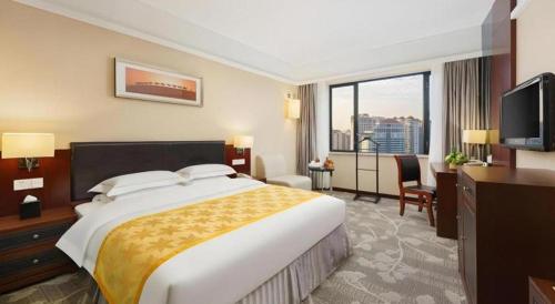 a hotel room with a large bed and a television at Shantou Golden Gulf Hotel in Shantou