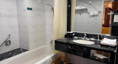 a bathroom with a sink and a bath tub at Shantou Golden Gulf Hotel in Shantou