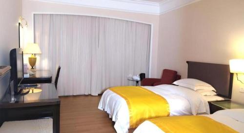 a hotel room with two beds and a desk at Shantou Golden Gulf Hotel in Shantou