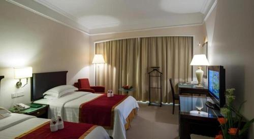 a hotel room with two beds and a television at Shantou Golden Gulf Hotel in Shantou