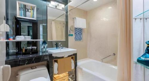 a bathroom with a toilet and a sink and a tub at Shantou Golden Gulf Hotel in Shantou