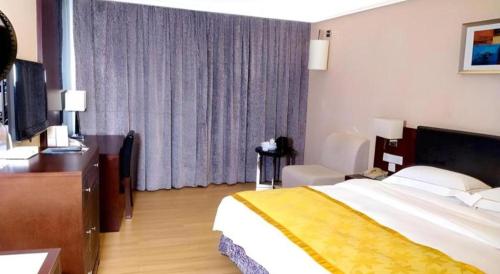 a hotel room with a large bed and a television at Shantou Golden Gulf Hotel in Shantou