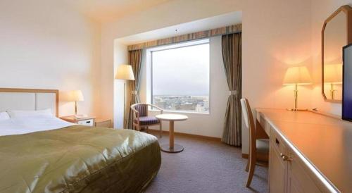 a hotel room with a bed and a window at Grand Hotel New Oji in Tomakomai