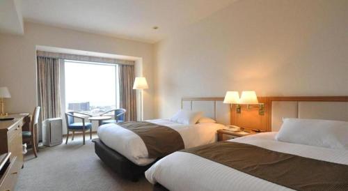 a hotel room with two beds and a table at Grand Hotel New Oji in Tomakomai