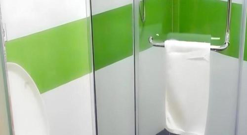 a green and white bathroom with a toilet paper dispenser at 7 Days Inn Siping Xinhua Street in Siping