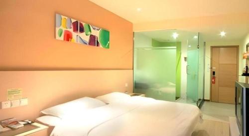 a bedroom with a white bed and a glass shower at 7 Days Inn Siping Xinhua Street in Siping