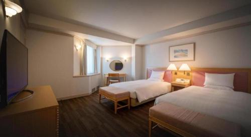 a hotel room with two beds and a flat screen tv at Air Terminal Hotel in Chitose