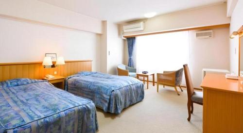 a hotel room with two beds and a table and a desk at Yuzawa New Otani in Yuzawa